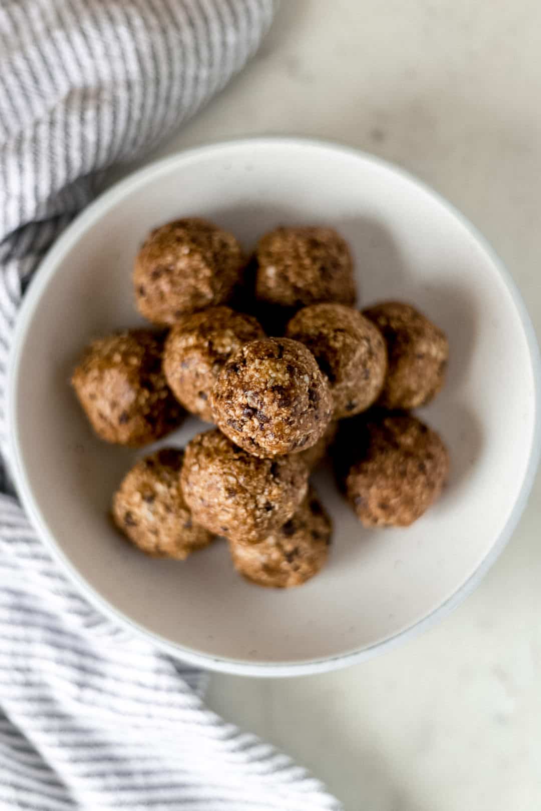 energy balls in large white bowl beside cloth napkin 