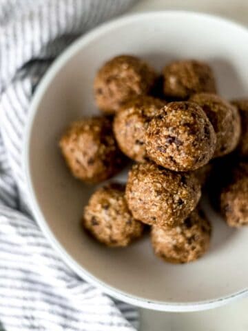 finished energy bites stacked on top of each other in large white bowl