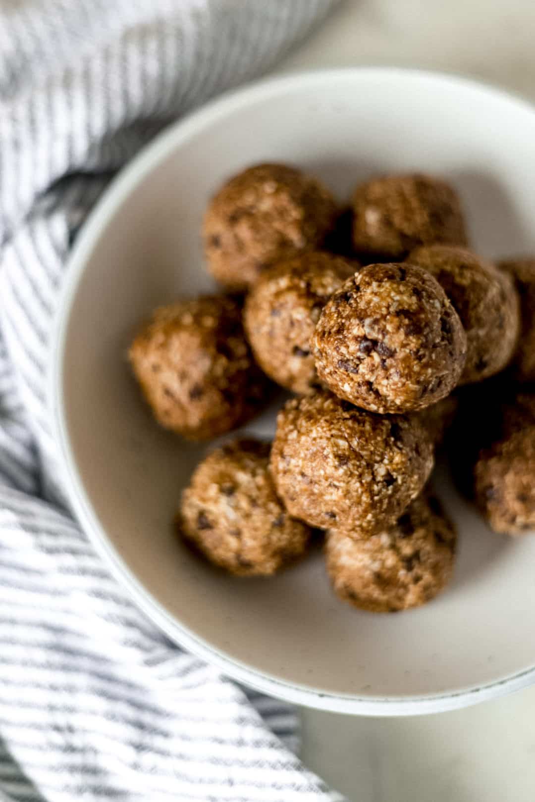 finished energy bites stacked on top of each other in large white bowl 