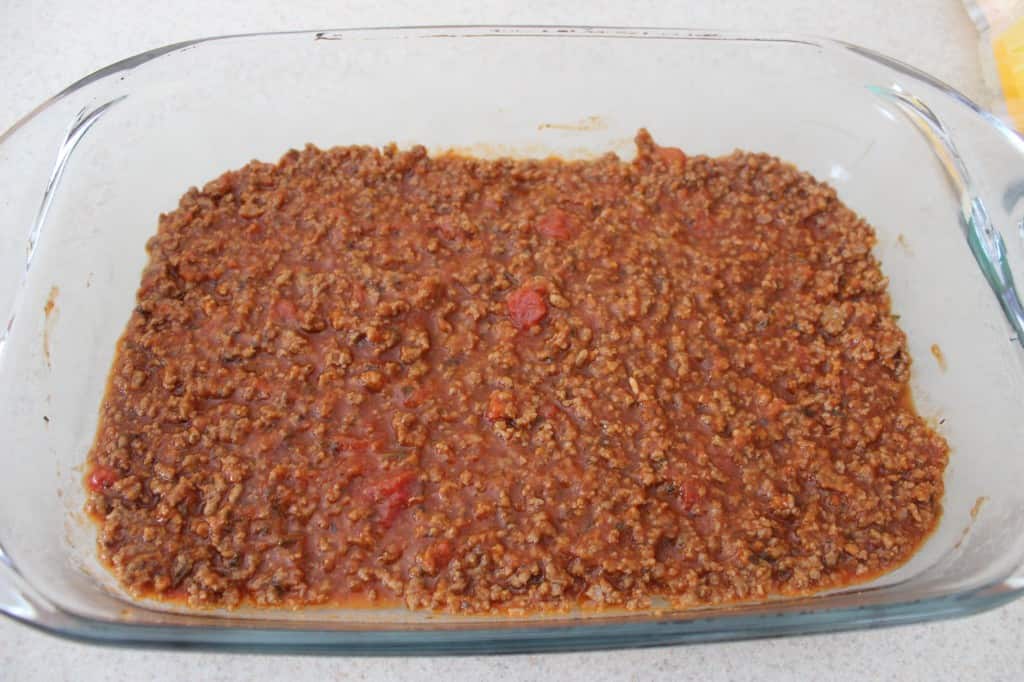 meat sauce at the bottom of a glass baking dish 