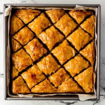 overhead view of finished baklava recipe in square baking pan lined with parchment paper