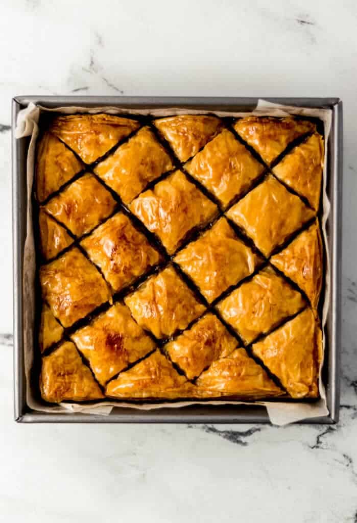 overhead view of finished baklava recipe in square baking pan lined with parchment paper