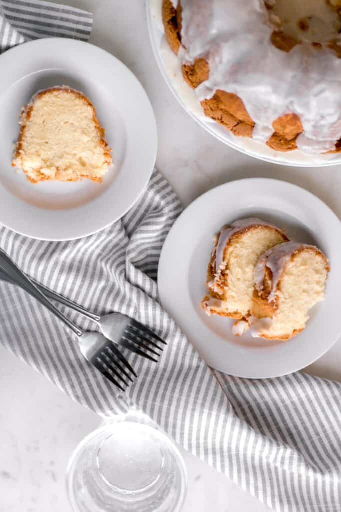 overhead view of slices of pound cake on white plate beside forks and cloth napkin