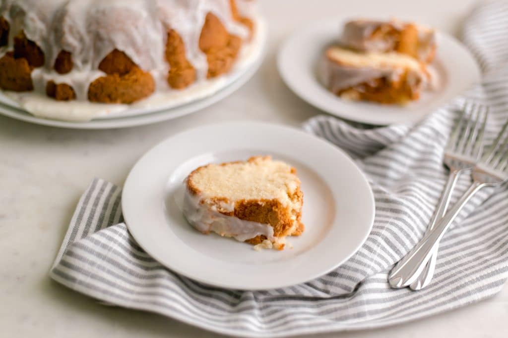 close up side view of slice of cake on white plate on top of cloth napkin