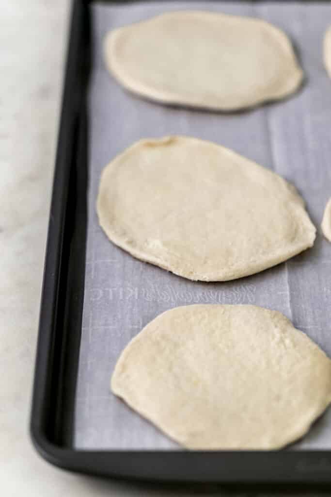 biscuit dough flattened on parchment lined baking sheet 