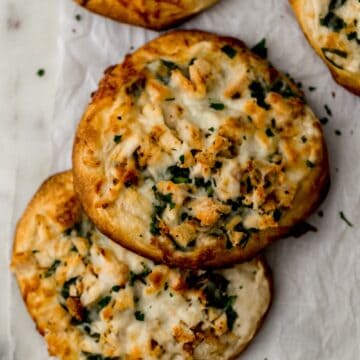 two chicken alfredo biscuit pizzas next to pizza cutter