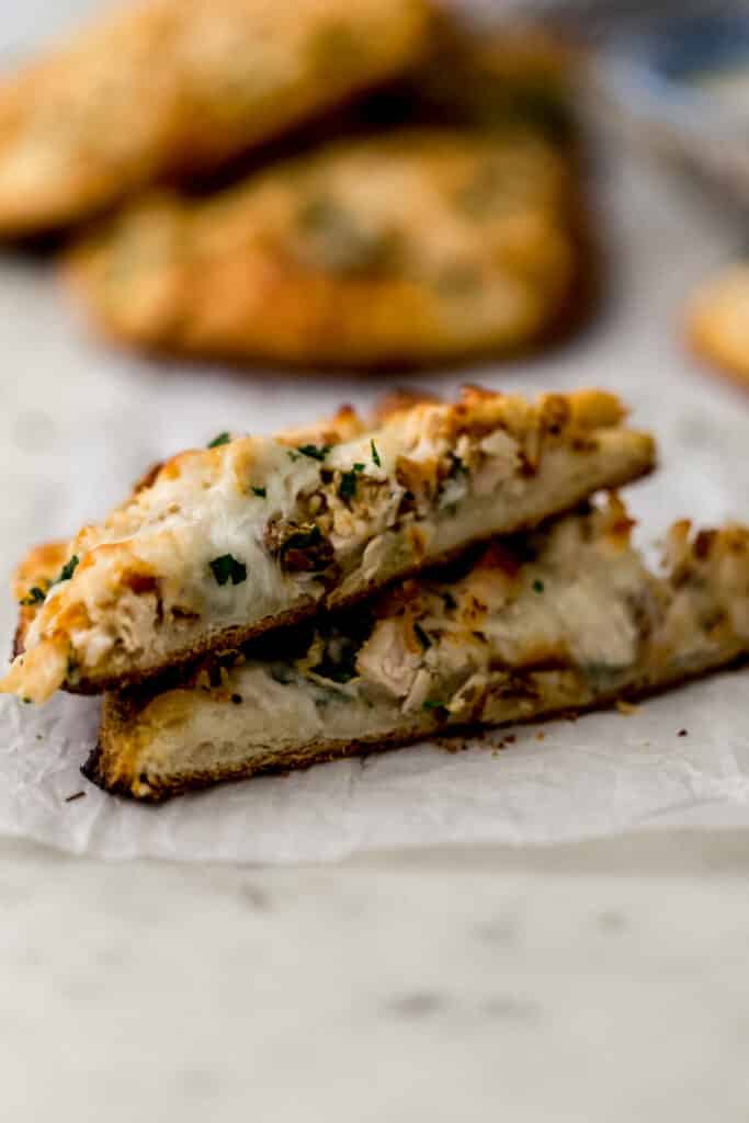 single alfredo biscuit pizza cut in half on parchment paper