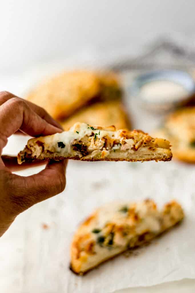 hand holding half of alfredo biscuit pizza 