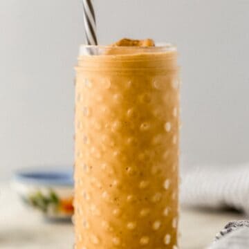 close up side view pumpkin spice smoothie in glass with straw
