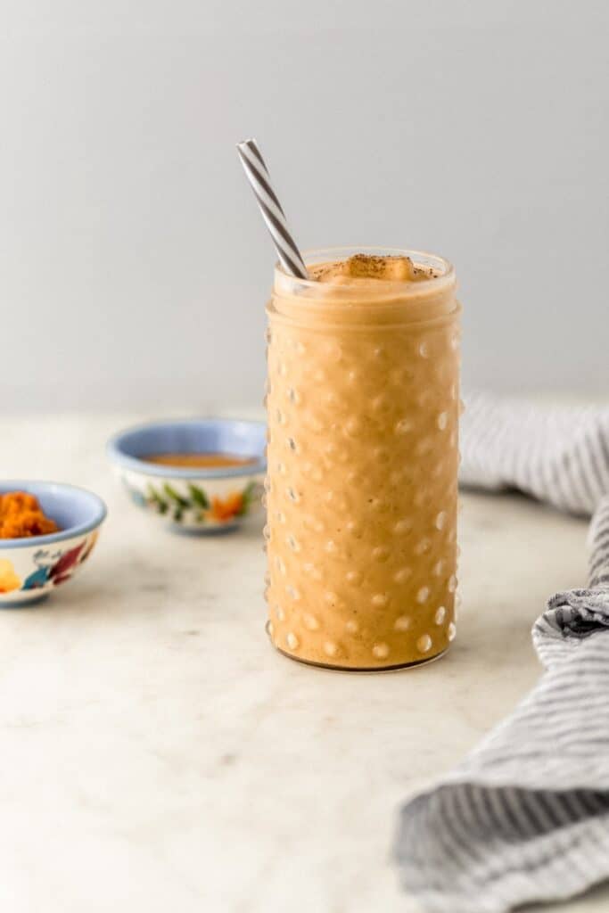 close up side view pumpkin spice smoothie in glass with straw