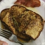 french toast on paper plate with for in it beside bacon