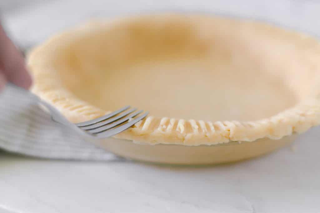fork on the side of unbaked pie crust 