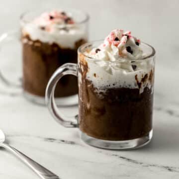 two finished mug cakes topped with whipped cream