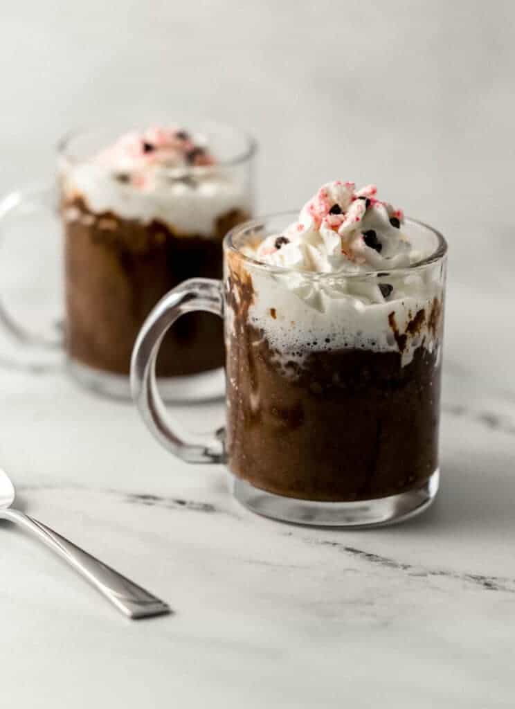 two finished mug cakes topped with whipped cream