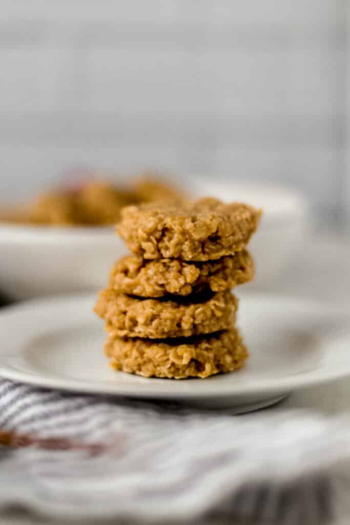Four no bake eggnog cookies stacked on top of each other on a white plate