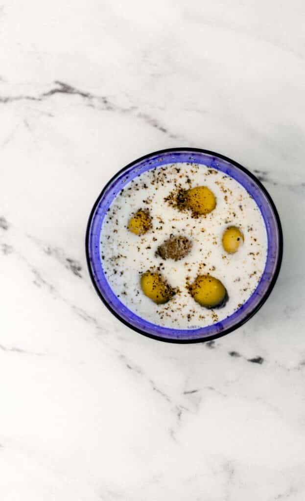 small blue bowl with eggs, milk, salt and pepper