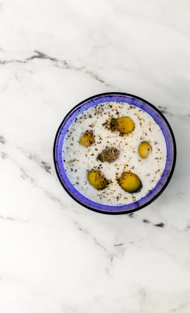 small blue bowl with eggs, milk, salt and pepper