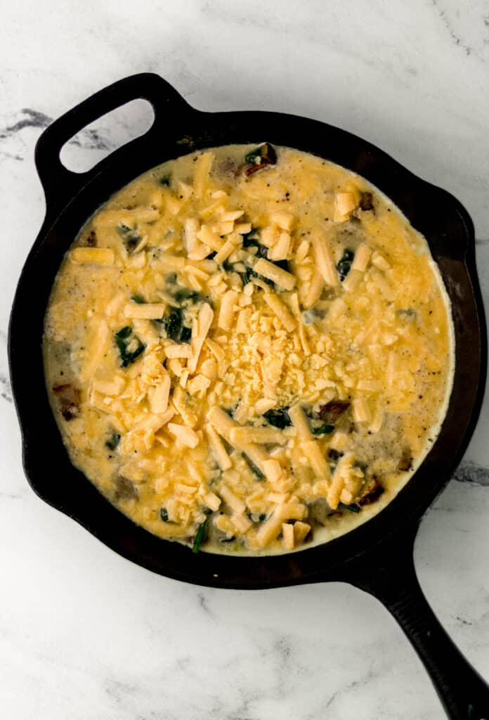 ingredients to make frittata mixed together in cast iron skillet