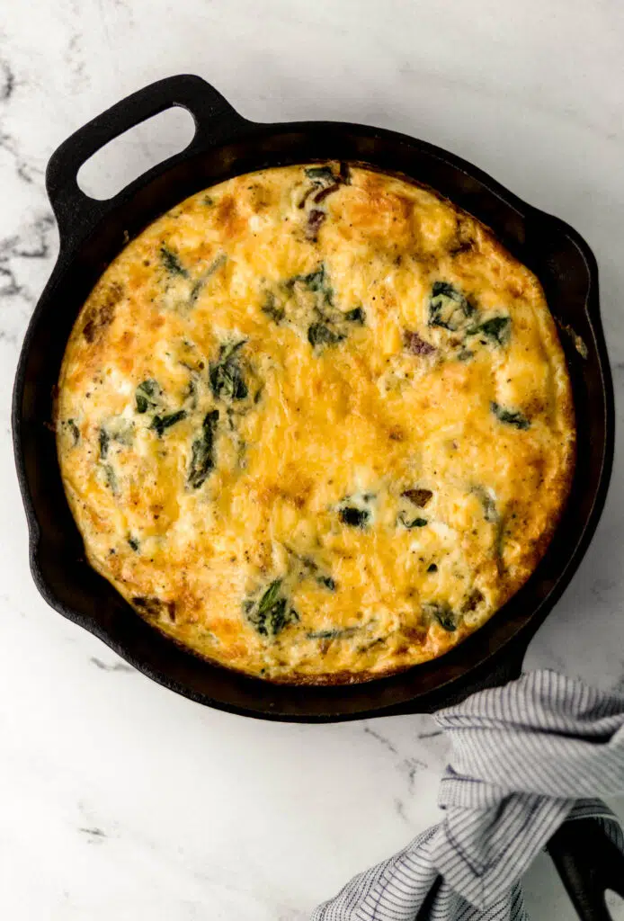 finished frittata in cast iron skillet with cloth napkin around handle
