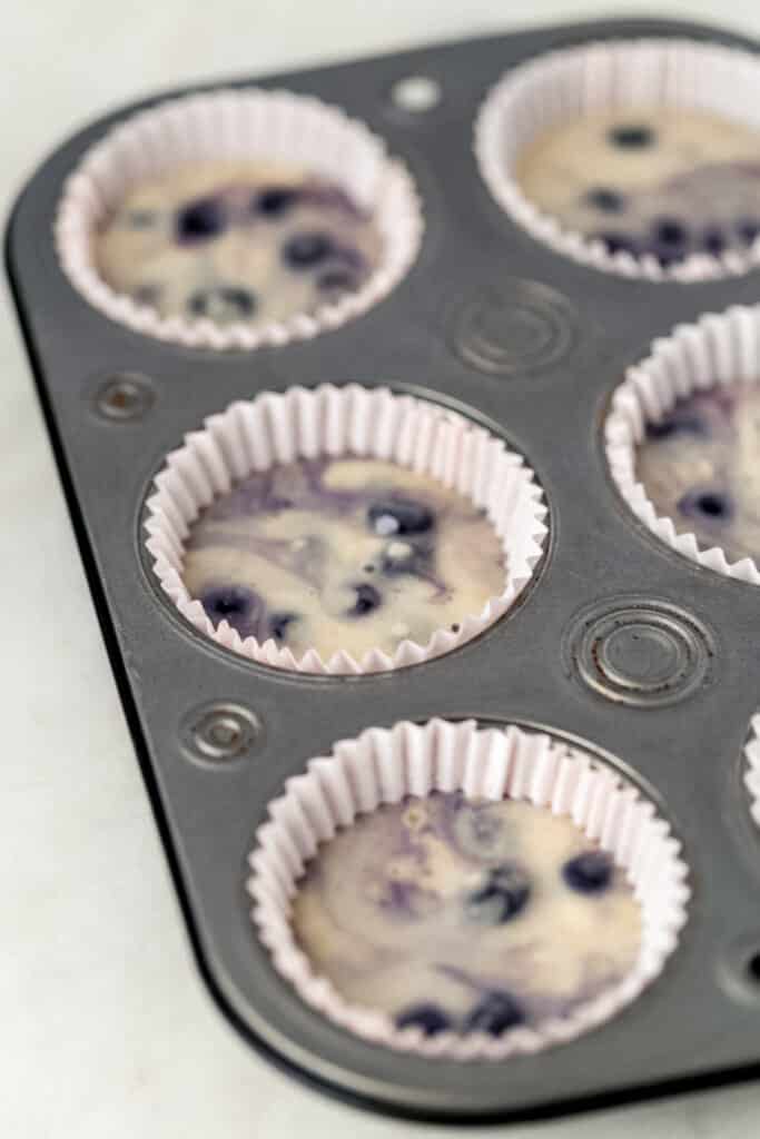 blueberry muffin mixture added to muffin pan before baking