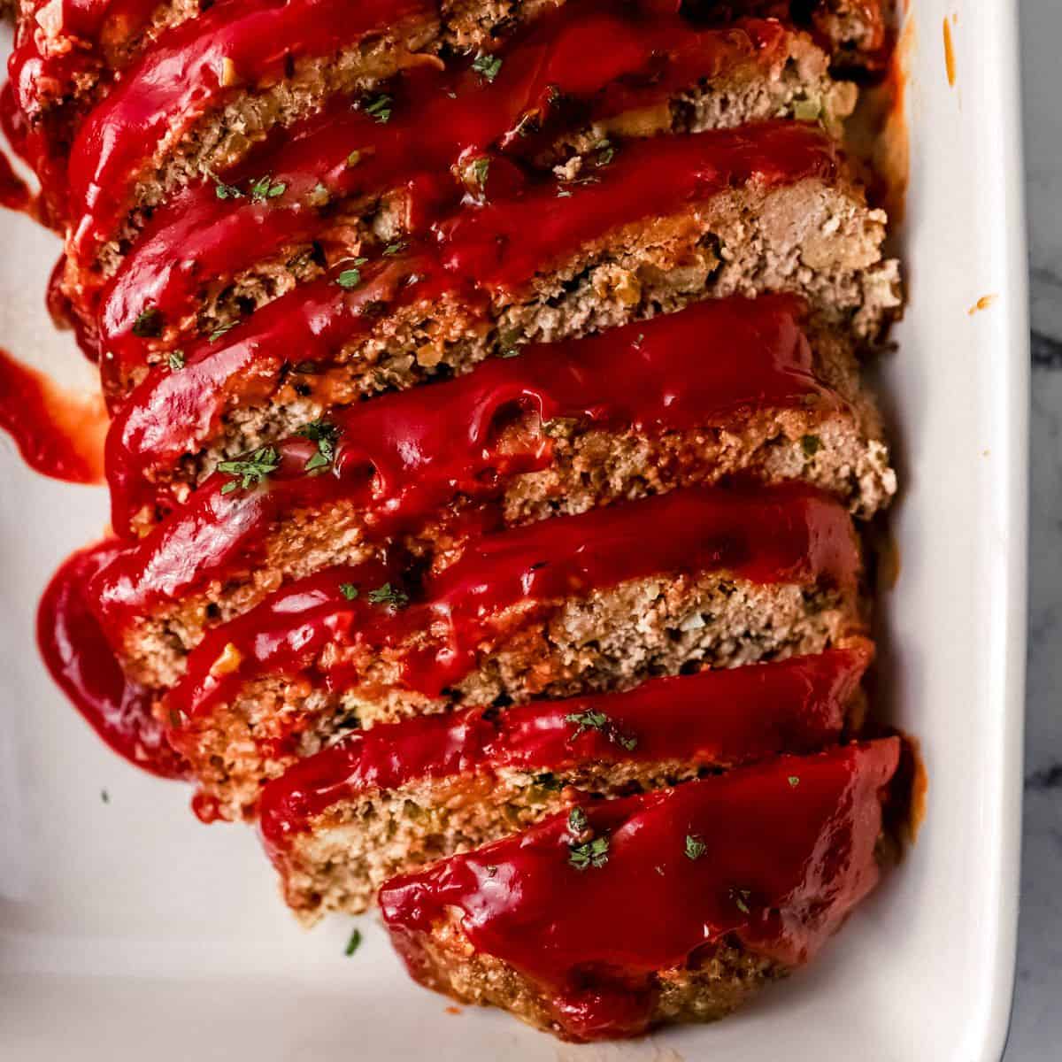 Overhead view of finished meatloaf in white baking dish.