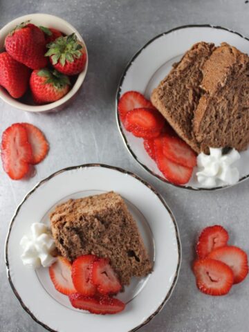 overhead view of slices of chocolate cake on white plates with slices of strawberries