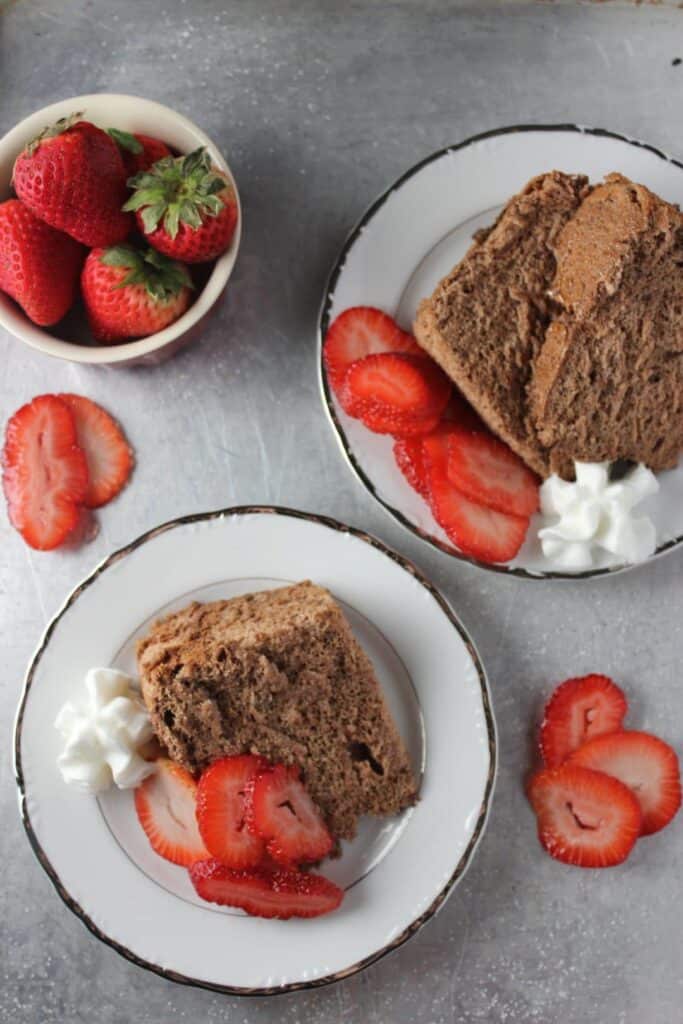 overhead view of slices of chocolate cake on white plates with slices of strawberries 