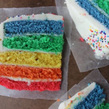 three slices of rainbow cake on wax paper