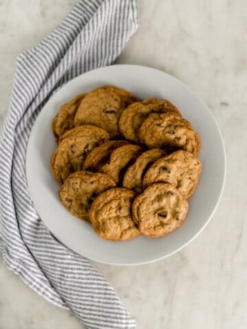 batch of chocolate chip cookies on white dinner plate with cloth napkin