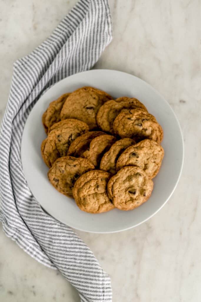 baked chocolate chip cookies on white dinner plate with cloth napkin 