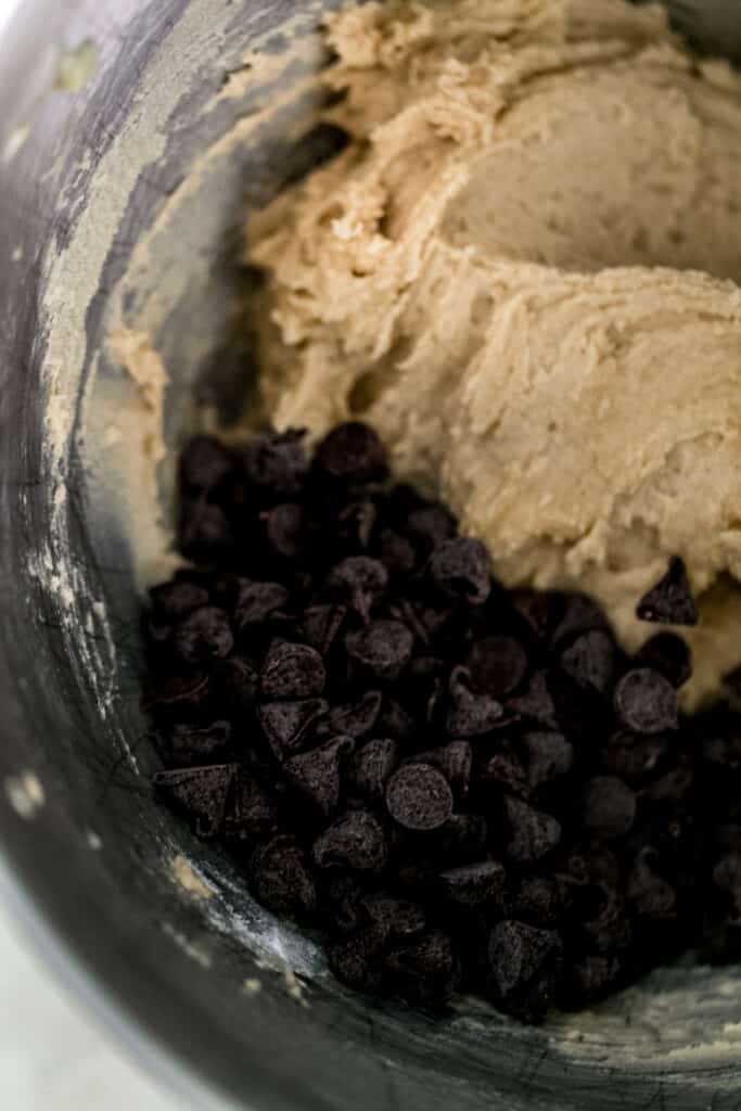 chocolate chips added to cookie mixture in stand mixer bowl