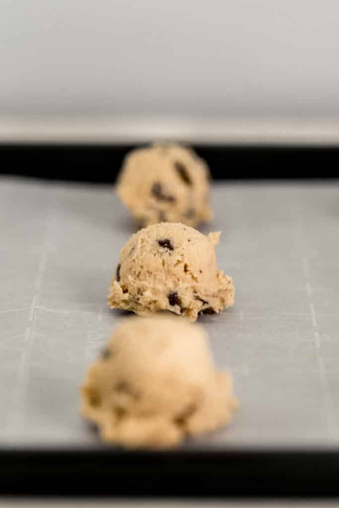 cookie dough scooped on to parchment lined baking sheet 