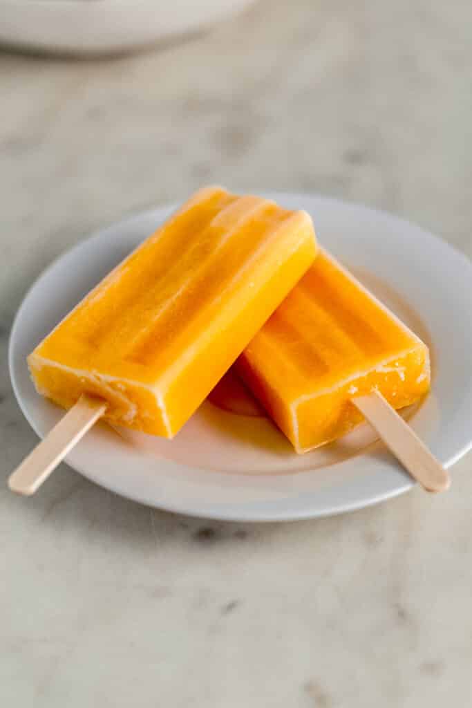 small white plate with two creamsicle popsicles on it