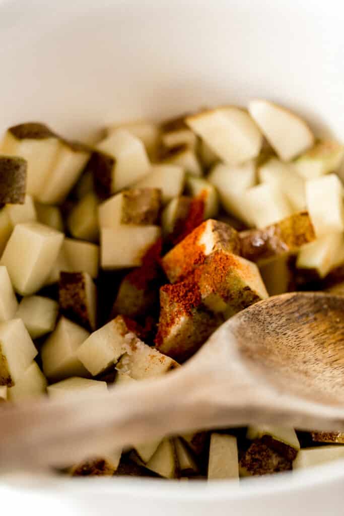 roasted potatoes in large white bowl topped with seasoning