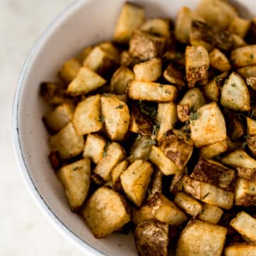 close up side view easy roasted potatoes in large white bowl