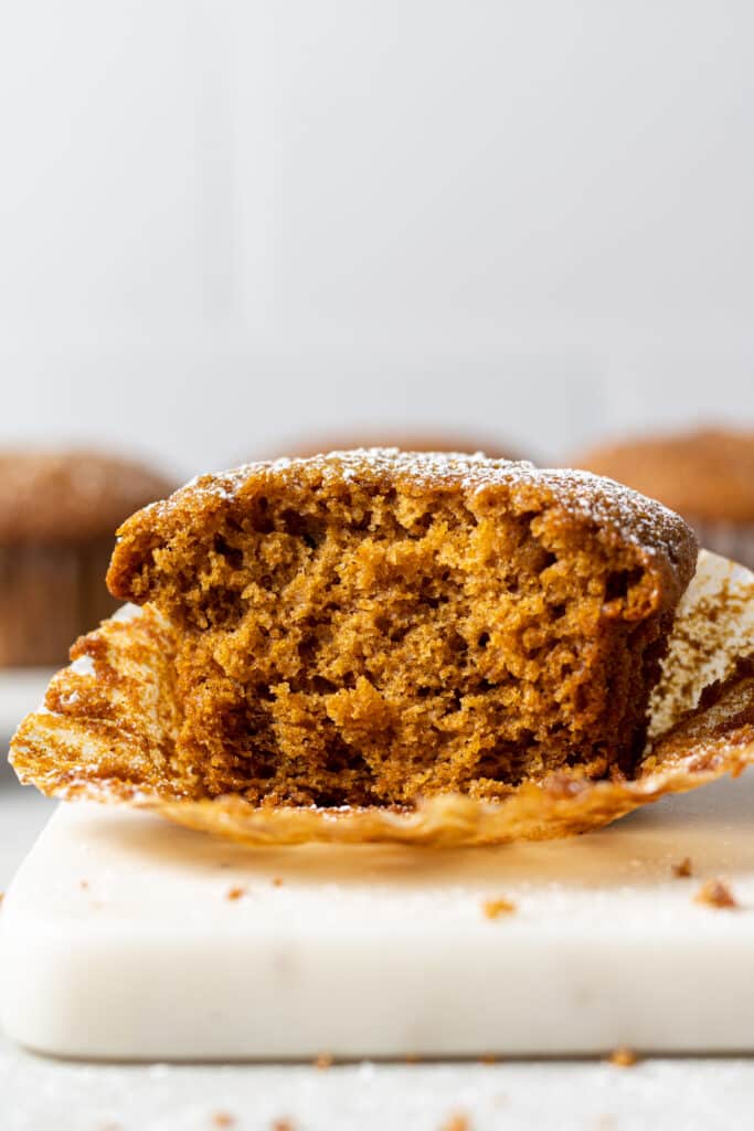 close up side view single gingerbread muffin cut in half on muffin liner