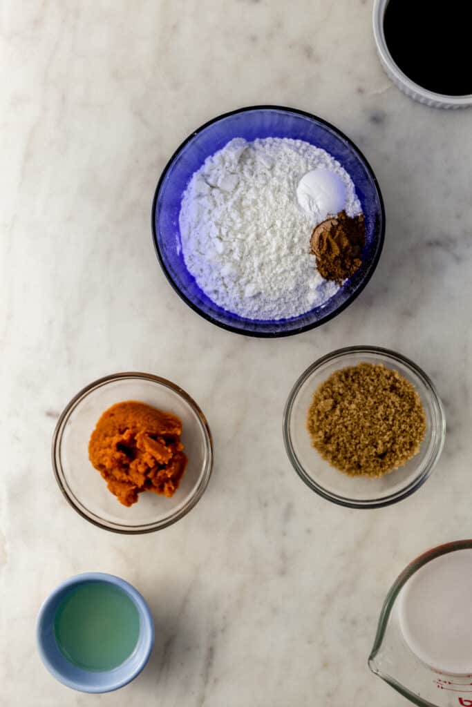 ingredients to make pumpkin spice latte waffles in small bowls on marble surface 