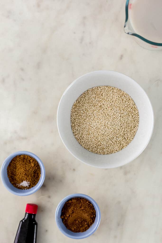 ingredients for chocolate quinoa in small bowls on marble surface