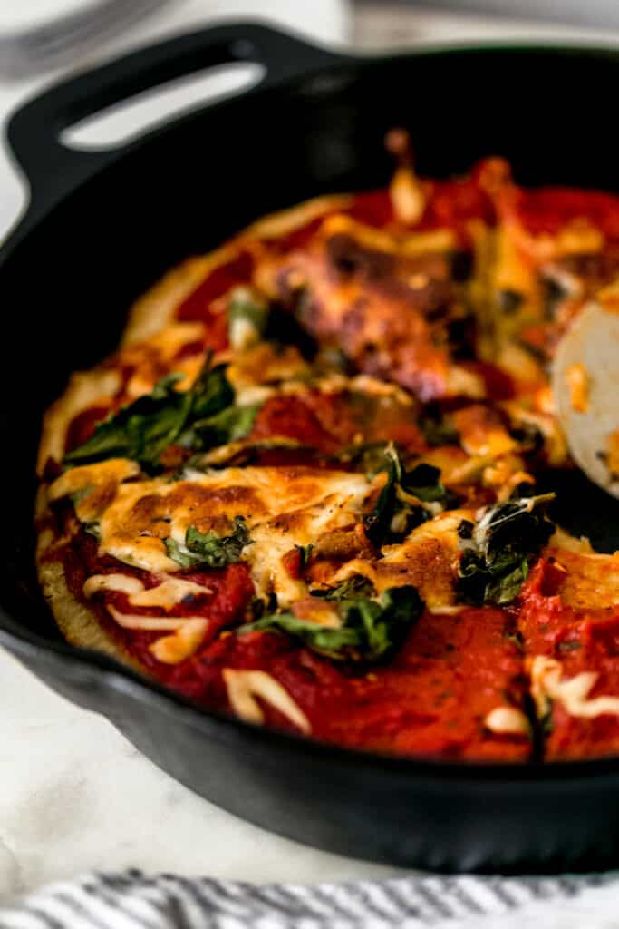 close up side view of homemade pizza that has been sliced in cast-iron skillet