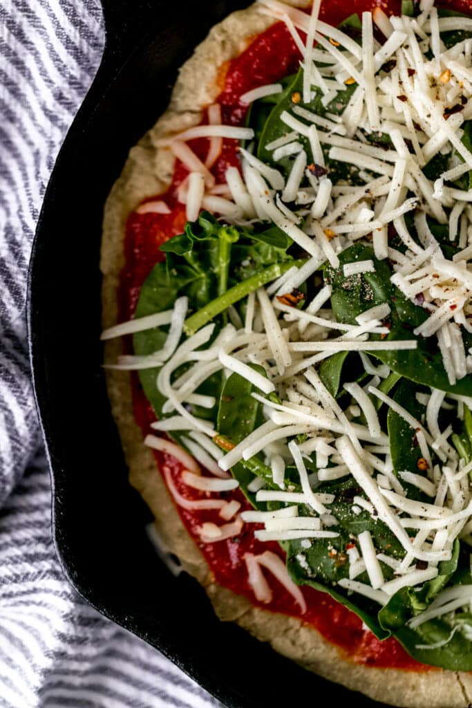 uncooked pizza in cast-iron skillet next to a stripped napkin