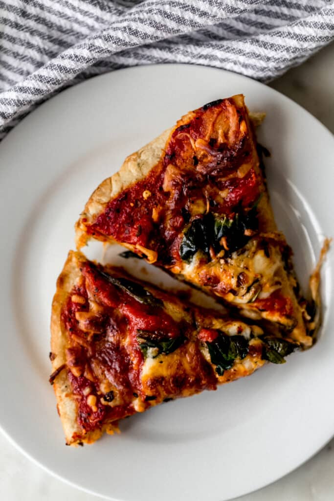 two slices of homemade pizza on white plate with napkin