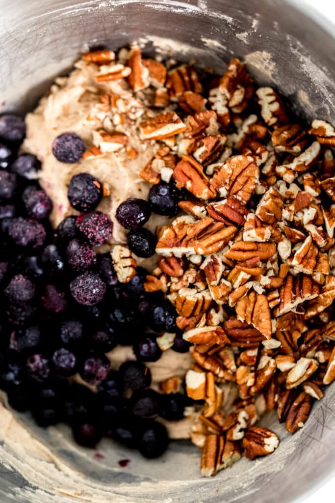 frozen blueberries and chopped pecans added to blueberry coffee cake mixture in stand mixer bowl. 