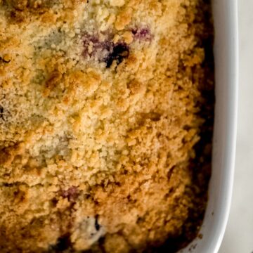 close up of blueberry coffee cake in white baking dish