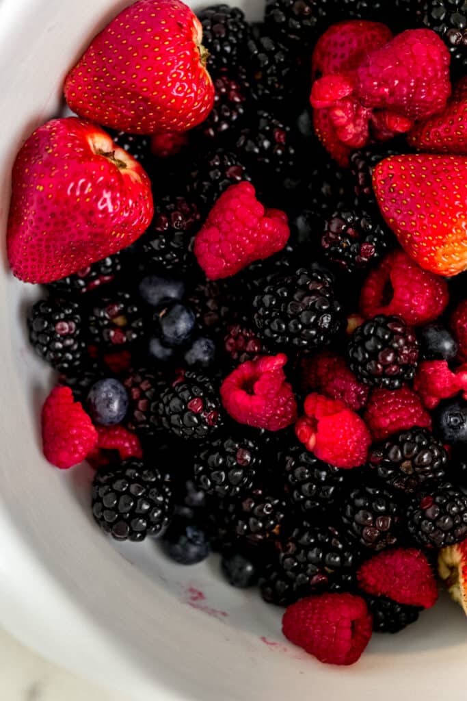 mixture of different kinds of berries in a large white mixing bowl 