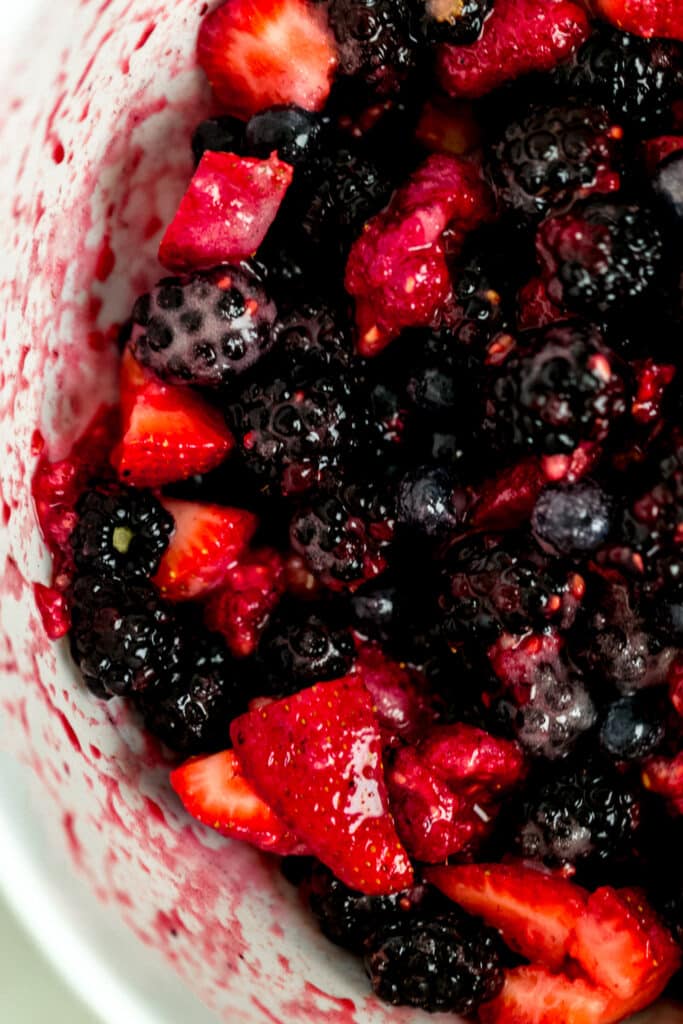 berries in white mixing bowl evenly coated with sugar mixture 