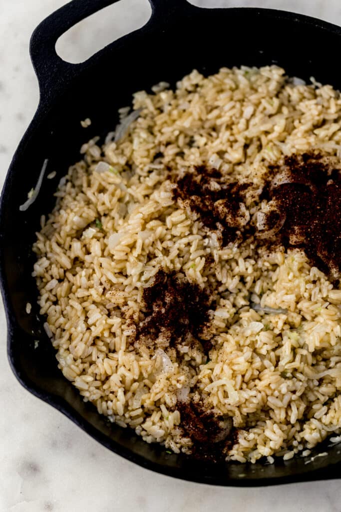 fried brown rice topped with chili powder in cast iron skillet 