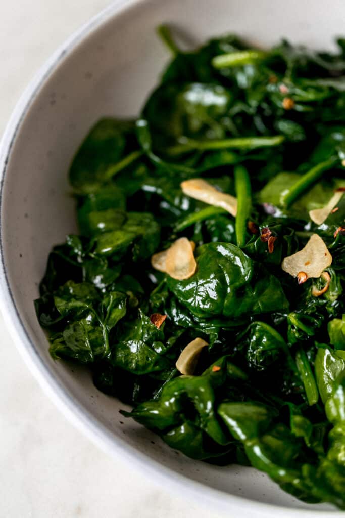 close-up side view sauteed garlic spinach in white bowl