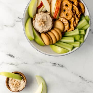 large white bowl with fruit, veggies, pretzels, and dip on it