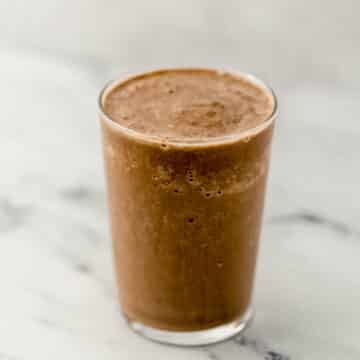 close up side view mocha smoothie in a glass on marble surface