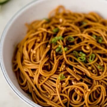 close up side view sesame noodles in white bowl